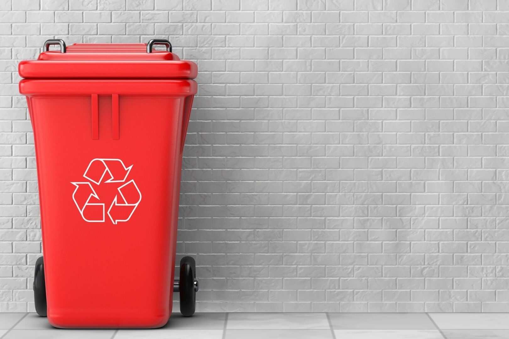 A red trash can sitting next to a brick wall.