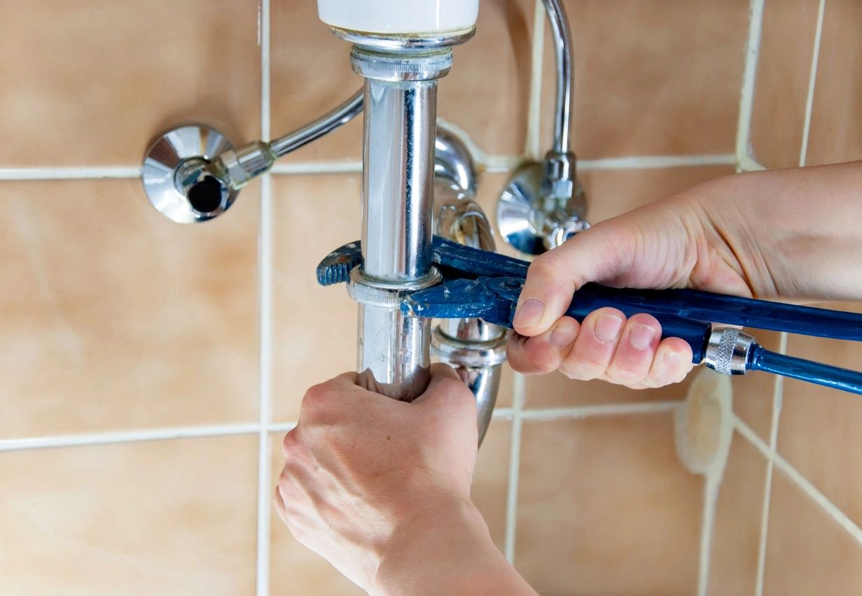 A person is fixing the faucet of a bathroom.